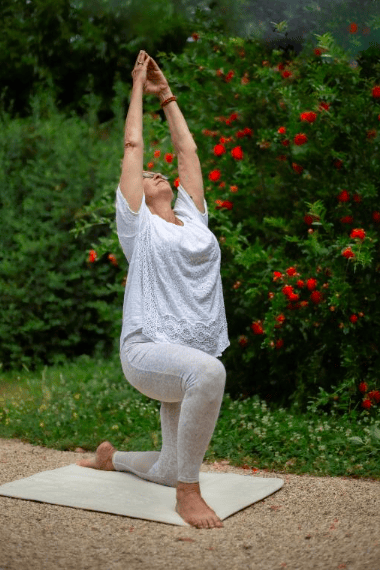 Posture de yoga en plein air, un genou au sol et les bras levés